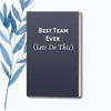 A notebook with a navy cover featuring the motivational phrase "Best Team Ever (Let's Do This)" in white text.