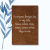 A notebook with a textured brown cover featuring the humorous phrase "Everyone Brings Joy to My Life: Some When They Enter, Some When They Leave."